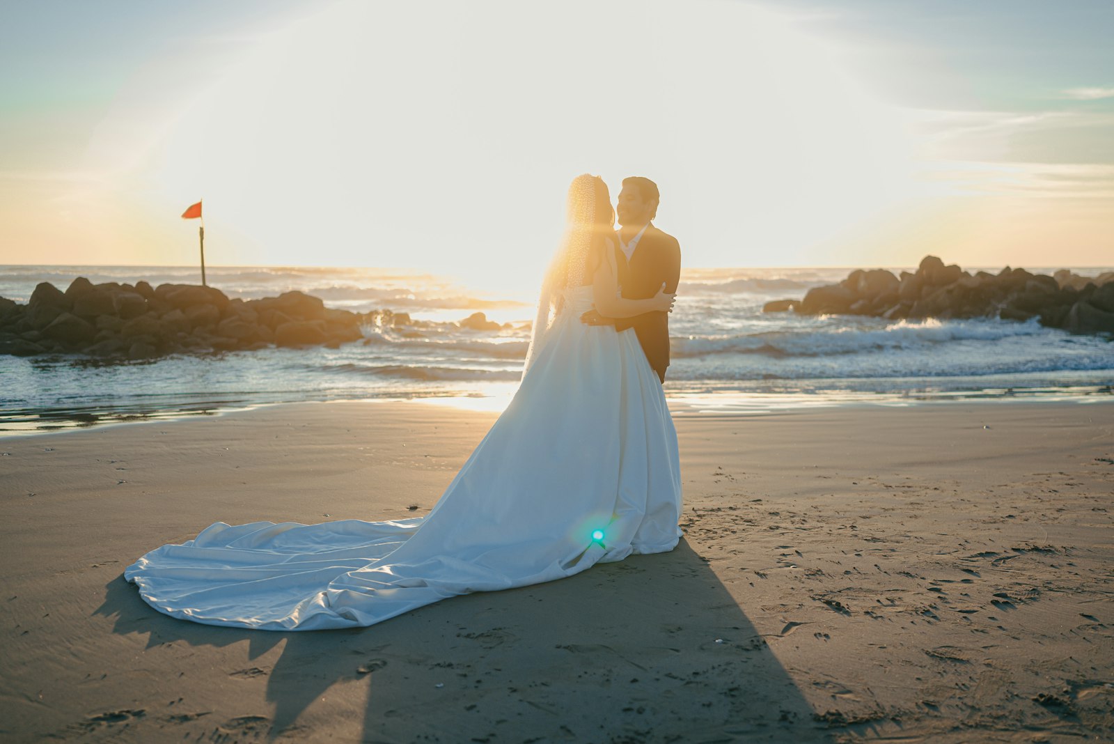 Bride and groom embracing on a beach at sunset