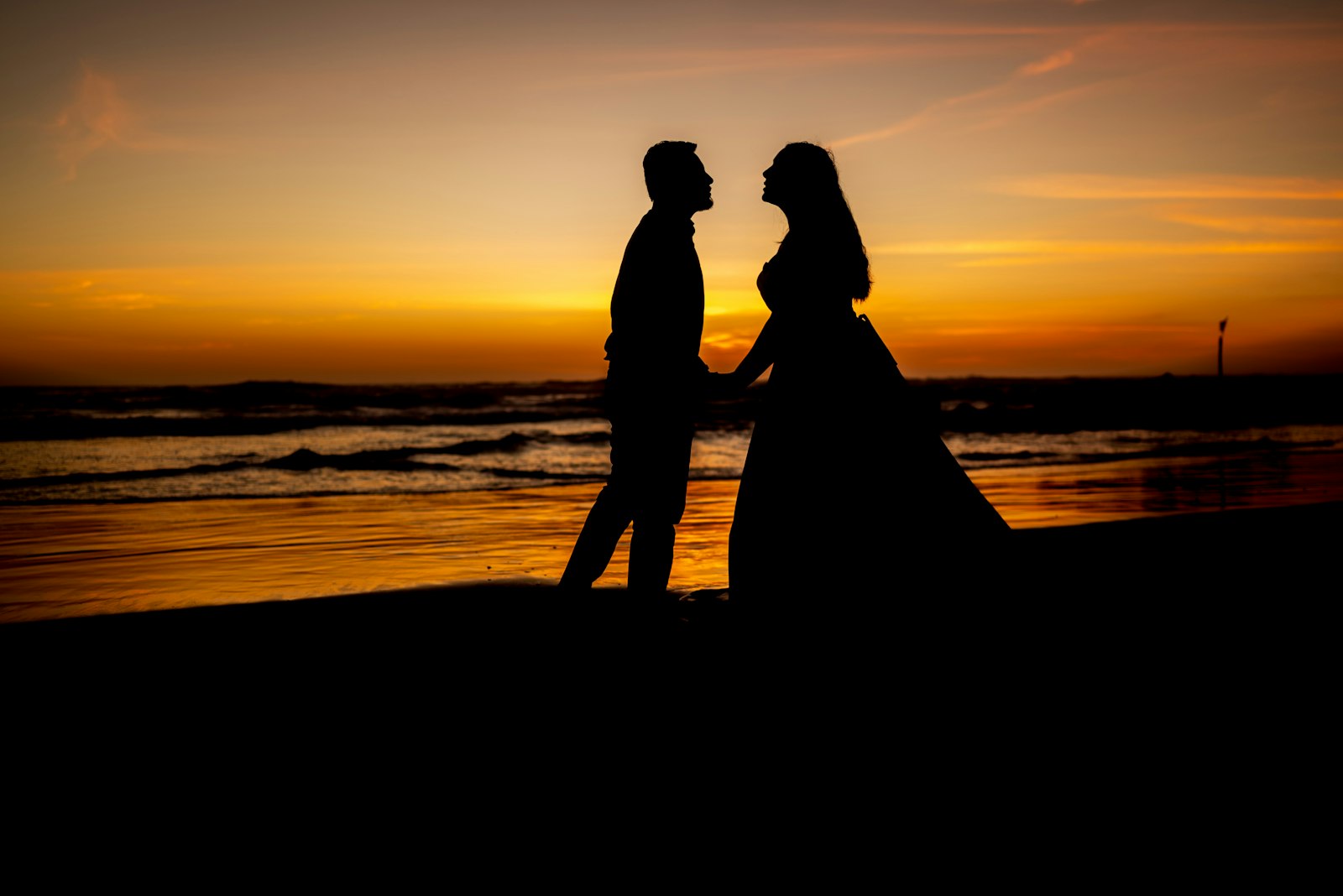 Couple holding hands on beach at sunset
