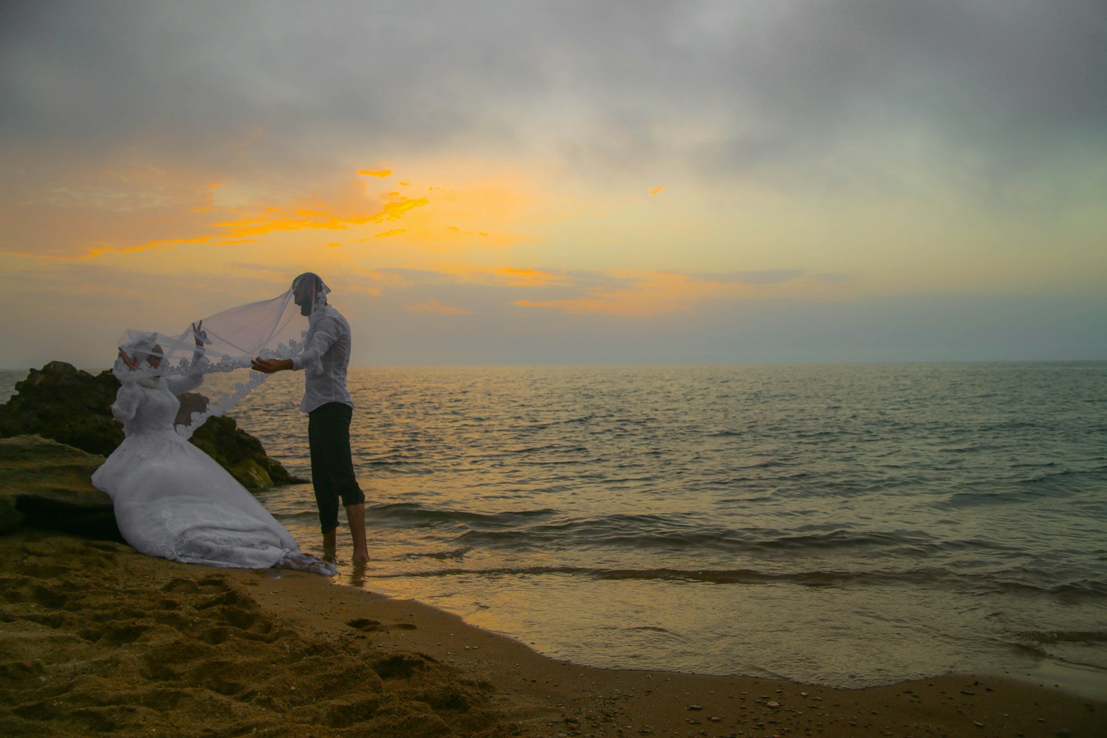 couple standing on beach during sunset